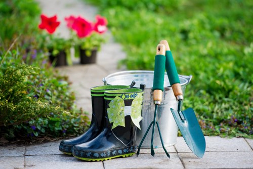 Trained operative using protective gear while trimming a tall hedge